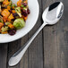 A bowl of food with a Walco Meteor stainless steel serving spoon on a table.