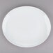 A Tuxton bright white china platter with a white rim on a gray surface.