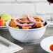 A close up of a white Thunder Group melamine swirl bowl filled with food.