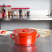 A red Thunder Group rice container with a lid on a counter.