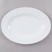 A white oval melamine platter with a white rim on a gray surface.