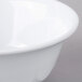A close-up of a white Thunder Group Imperial melamine bowl with a white scalloped rim.