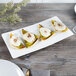 A Villeroy & Boch white bone porcelain rectangular plate with appetizers on it.