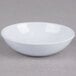 A white Thunder Group coupe sauce dish on a grey surface.