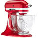 A KitchenAid Candy Apple Red countertop mixer with clear bowl.