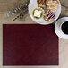 A rectangle faux leather placemat with a plate of pastries and a cup of coffee on it.