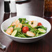 A white melamine bowl filled with salad with shrimp and vegetables.