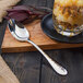 A Walco stainless steel dessert spoon on a wood surface.