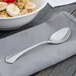 A Walco stainless steel teaspoon on a napkin next to a bowl of oatmeal with fruit.