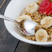 A Walco stainless steel teaspoon in a bowl of oatmeal with bananas and strawberries.