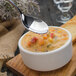 A Walco Freya stainless steel bouillon spoon lifting soup with vegetables.