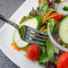 A Walco stainless steel salad fork in a vegetable salad.