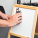 A person's hand using an Expo Soft Pile whiteboard eraser to erase a whiteboard.