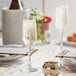 A table setting with Acopa Radiance flute glasses filled with champagne on a table with food.