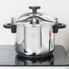 A silver Monix stainless steel pressure cooker on a stove.