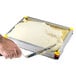 A hand using a Matfer Bourgeat yellow Mousse Frame to cut a white dessert.