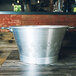 A Matfer Bourgeat aluminum conical colander with handles and base on a wood surface.