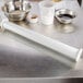 A Matfer Bourgeat stainless steel adjustable thickness rolling pin on a metal surface with bowls and dough.