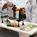A chef using a Bron Coucke Le Rouet manual spiral vegetable slicer to cut vegetables.