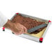 A hand using a knife to cut a chocolate cake in a Matfer Bourgeat mousse frame.