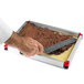 A hand using a knife to cut a chocolate cake in a Matfer Bourgeat yellow mousse frame.