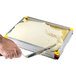 A hand using a Matfer Bourgeat yellow mousse frame to cut white dessert.