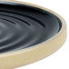 A black Chef & Sommelier stoneware plate with a wavy rim.