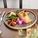 A Chef & Sommelier Geode gray stoneware dinner plate with food and a fork on a table.