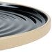 A black ceramic Chef & Sommelier dinner plate with a wavy edge.