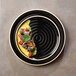A Chef & Sommelier black stoneware dinner plate with food on it.