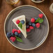 A Chef & Sommelier gray stoneware plate with a piece of cheesecake and berries on top.