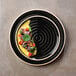 A Chef & Sommelier black stoneware plate with food on it.