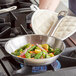 A hand using a Vigor stainless steel fry pan to cook vegetables on a stove.