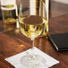 A Libbey white wine glass filled with white wine on a table.