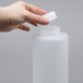 A person holding a white plastic FIFO Innovations squeeze bottle with a lid.