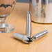 Three stainless steel iSi decorator tips on a table with metal objects.
