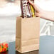A hand holding a Duro Natural Kraft paper bag full of candy.