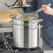 A woman using a Vigor stainless steel double boiler on a stove to whisk food.