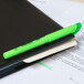 A Bic Brite Liner Fluorescent Green pen on a black notebook.