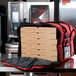 A red Rubbermaid insulated delivery bag with pizza boxes inside.
