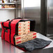A red Rubbermaid insulated pizza delivery bag with pizza boxes inside.