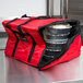 A red Rubbermaid insulated delivery bag with food inside.