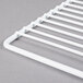 A white coated wire grid shelf for an Avantco deli or display case.