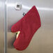 A red and white San Jamar Cool Touch Flame oven mitt hanging on a refrigerator.
