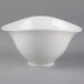 A white Villeroy & Boch Dune porcelain bowl with a curved edge on a gray background.
