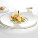 A Villeroy & Boch white bone porcelain flat plate with a well of brown liquid and green vegetables.