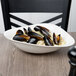 A white porcelain Villeroy & Boch Dune deep bowl filled with mussels on a table.