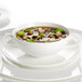 A white Villeroy & Boch bone porcelain bouillon cup with soup and a spoon in it.