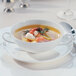 A white Villeroy & Boch bone porcelain bouillon cup filled with soup on a plate.
