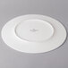 A white Villeroy & Boch flat coupe plate with a circular design on a gray surface.